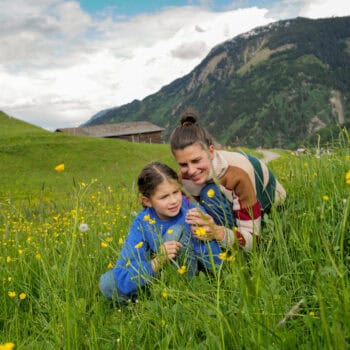 Mama und Tochter betrachen eine Blume in den Schweizer Bergen