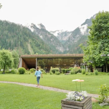 Kind spaziert durch grünen Garten in nden Bergen.